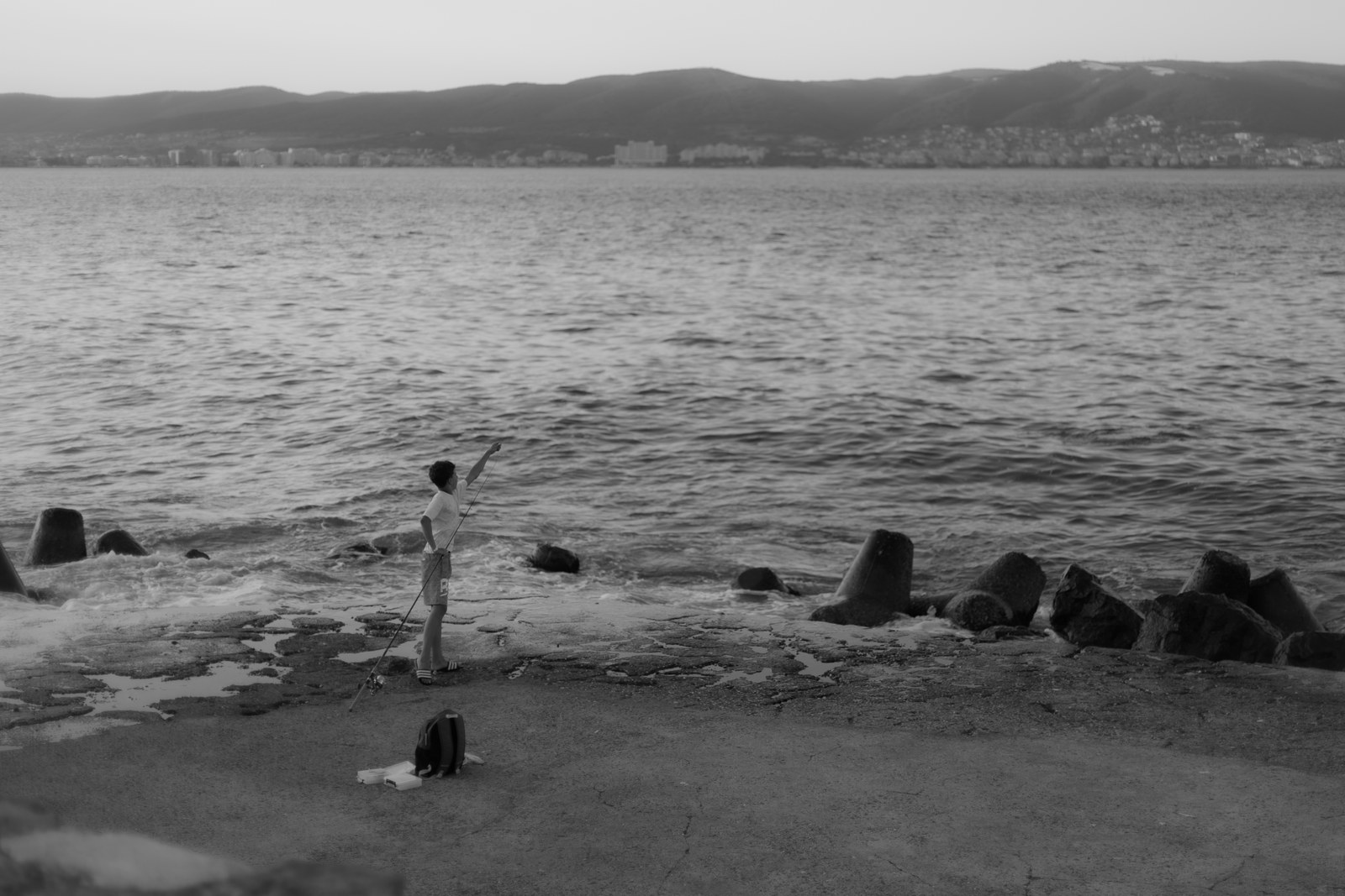 Boy fishing by the sea, black and white
