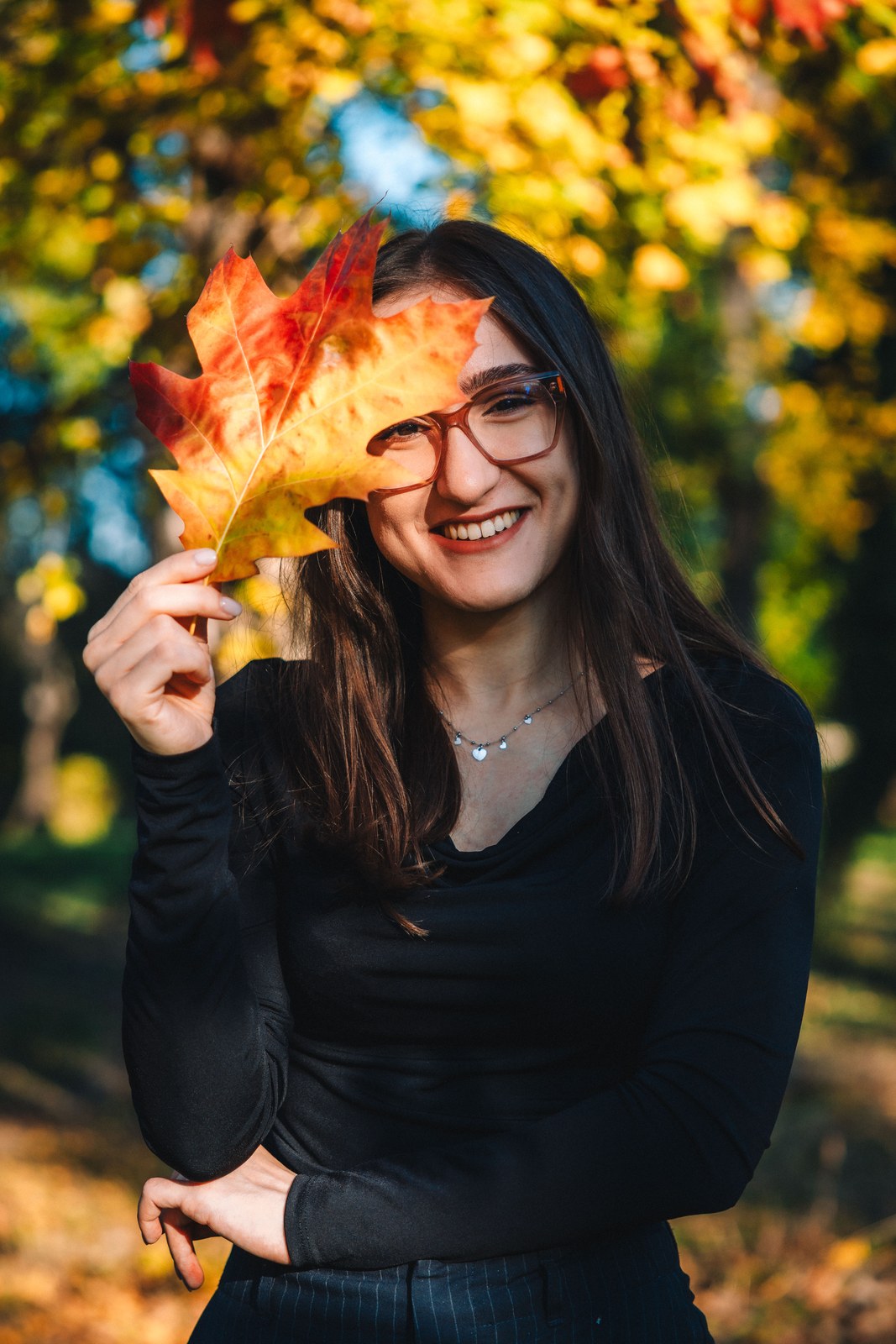 Smiling woman holding an autumn leaf